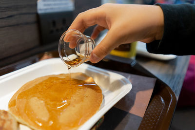 Hand pouring syrup on pancake. breakfast concept