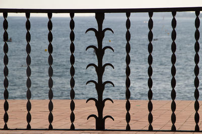 Close-up of metal fence against sea