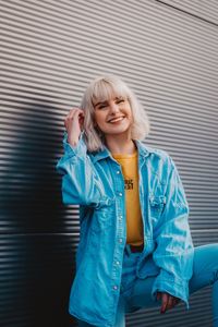 Portrait of happy young woman standing against wall