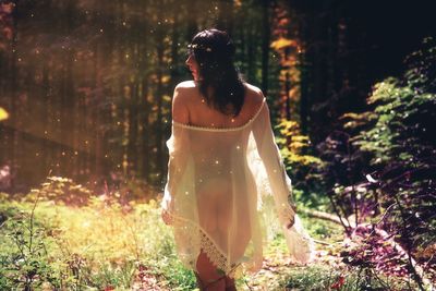 Rear view of woman standing against trees at night