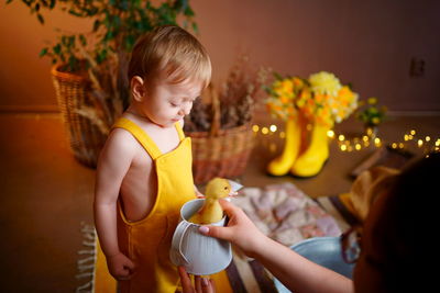 Baby in yellow jumpsuit with goose for easter