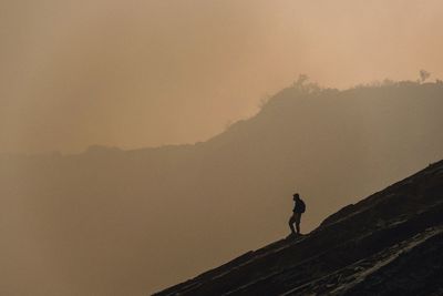 Silhouette of man standing on mountain against sky
