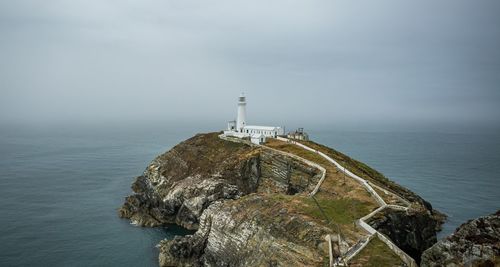 Lighthouse by sea against sky