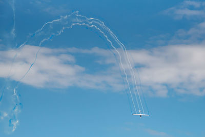 Low angle view of vapor trails with airplane flying in sky