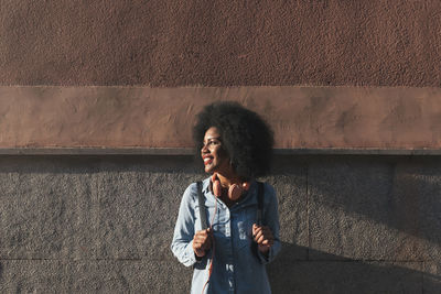 Young woman standing against wall
