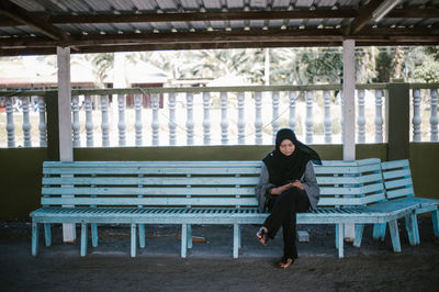 Woman using mobile phone while sitting on bench