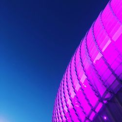 Low angle view of illuminated ferris wheel against blue sky