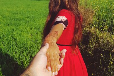 Woman holding cropped hand on field