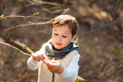 Cute boy looking at his hand in spring forest