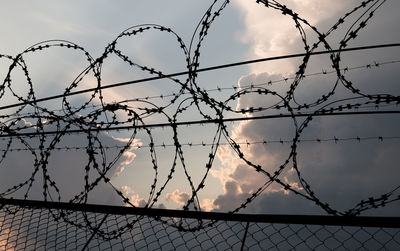 Low angle view of barbed wire against sky during sunset