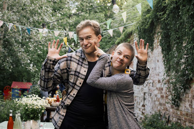 Portrait of playful friends making faces and gesturing at dinner party in back party