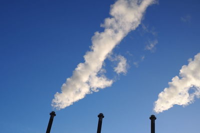 Low angle view of smoke stack against blue sky