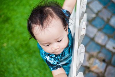 Close-up of baby girl standing on fence