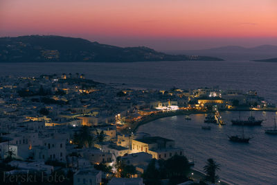 High angle view of city by sea against sky at sunset