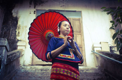 Young woman with umbrella while wearing traditional clothes