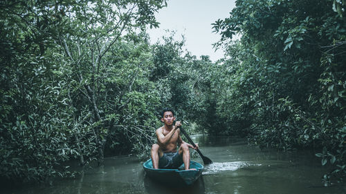Portrait of young woman sitting on tree in forest