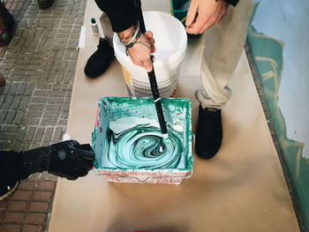 Low section of people standing by paint bucket