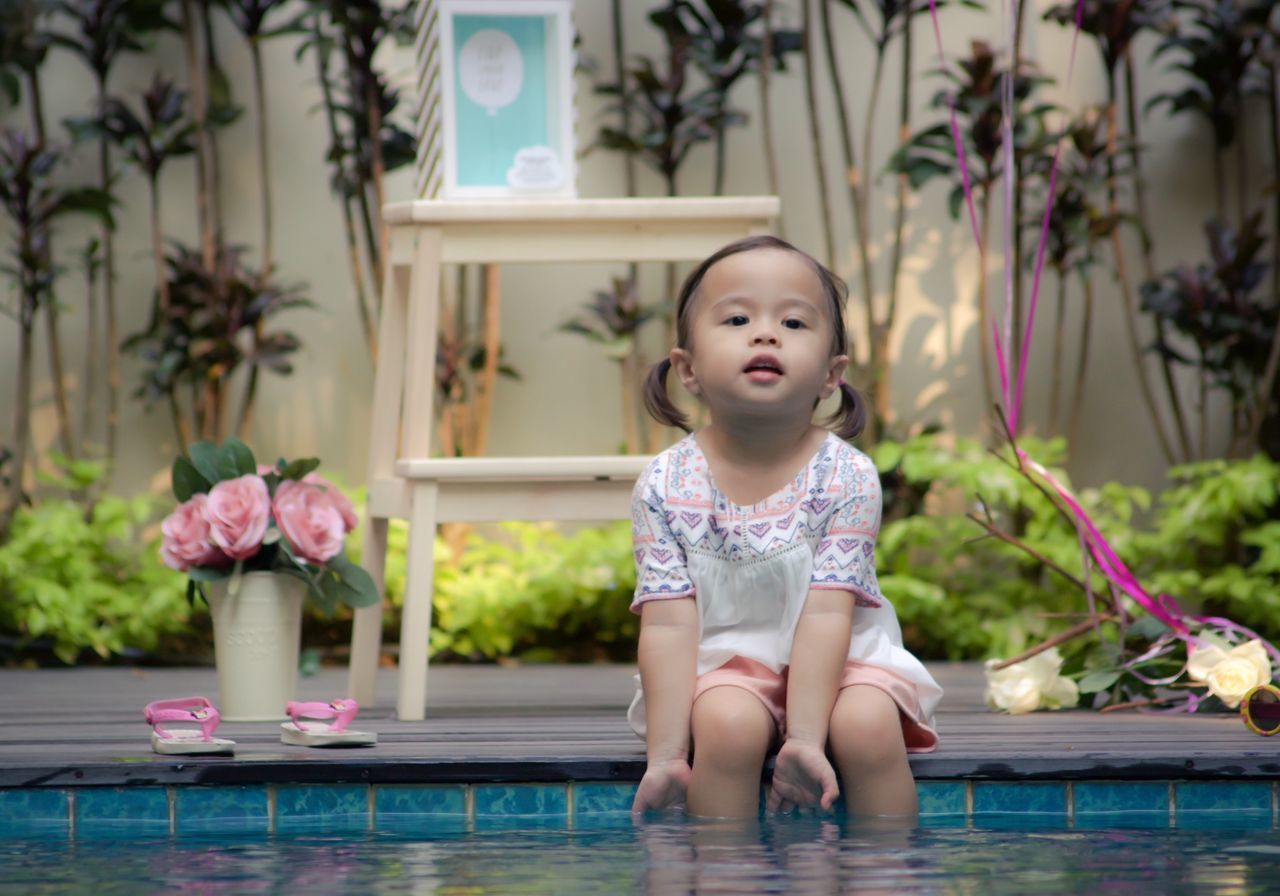 CUTE GIRL SITTING ON SWIMMING POOL