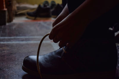 Low section of person tying shoe on floor