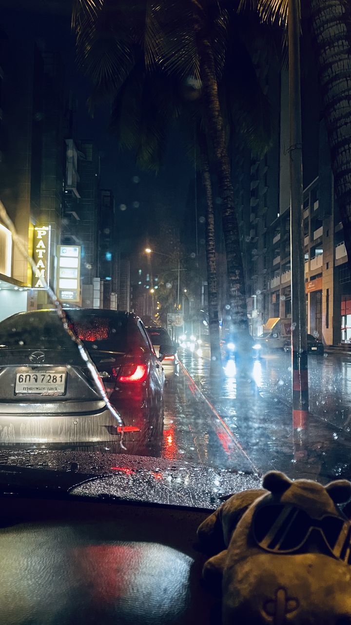 car, motor vehicle, mode of transportation, transportation, city, night, architecture, street, illuminated, road, land vehicle, darkness, light, rain, building exterior, built structure, wet, city street, city life, traffic, evening, vehicle, sign, travel, nature, no people, reflection, outdoors, motion, taxi, travel destinations, headlight, tail light, water