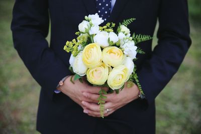 Low section of man holding bouquet