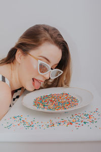 Close-up of woman wearing sunglasses with confetti against gray background