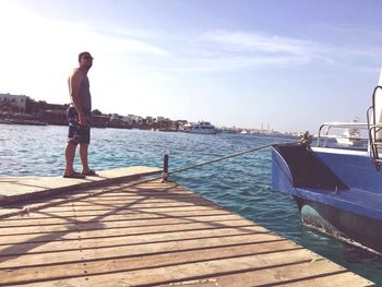 Man standing on pier over sea against sky