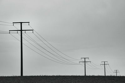 Low angle view of electricity pylon on field against sky