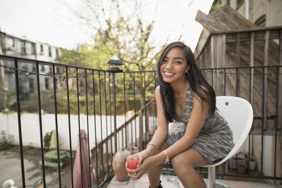 Young woman with a cocktail on her balcony