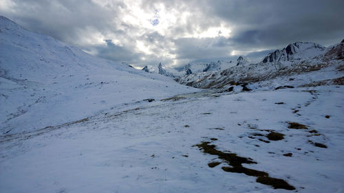 Scenic view of snowcapped mountains against cloudy sky