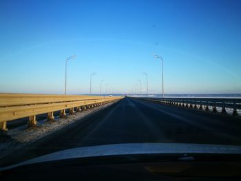 Road seen through car windshield against blue sky