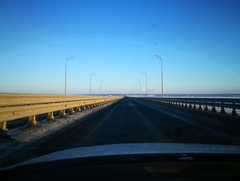 Road against clear blue sky seen through car windshield