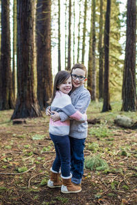 Brother and sister hugging in the forest.