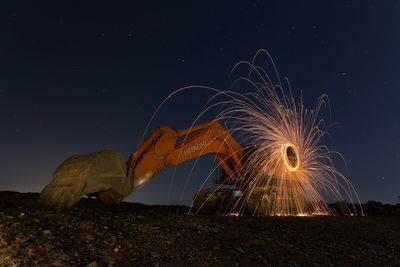 Illuminated ferris wheel on beach against sky at night