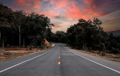 Road amidst trees against sky during sunset