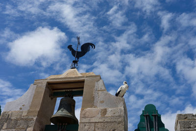 Low angle view of statue on building against sky