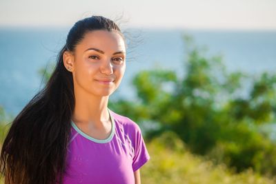 Portrait of smiling young woman standing against sky
