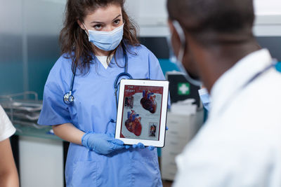 Doctor wearing mask showing digital tablet doctor