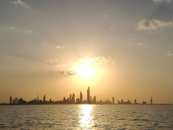 Panoramic view of sea and buildings against sky during sunset