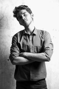 Portrait of young man standing against wall