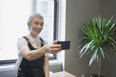 Young woman smiling while checking her smart phone in office space.