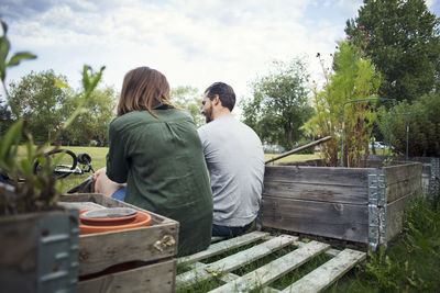 Rear view of friends standing against plants