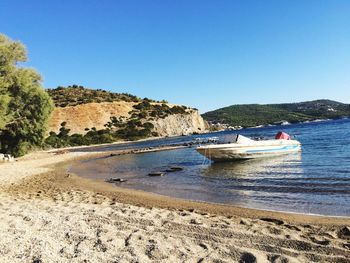 Boats in sea against clear blue sky