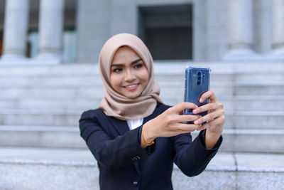 Portrait of woman photographing with mobile phone