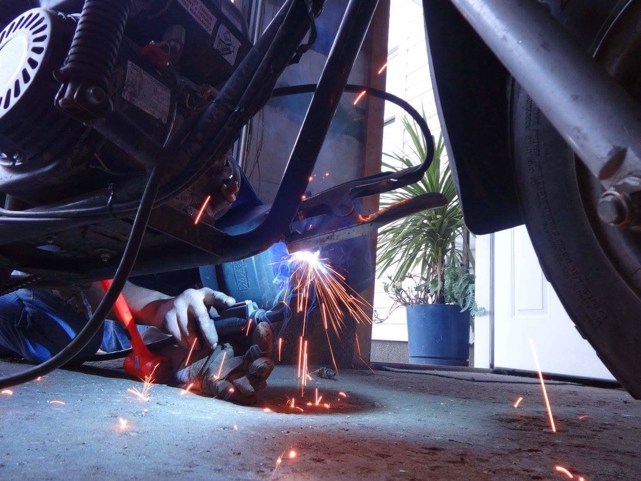 Low angle view of worker welding motorcycle
