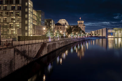 Illuminated bridge over river in city at night