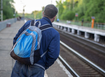 Rear view of man walking on railway track