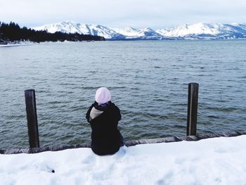 Full length of man on snowcapped mountains by lake during winter