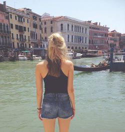 Young woman standing on water against buildings