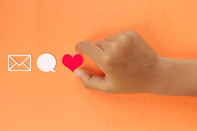 Close-up of hand against orange wall
